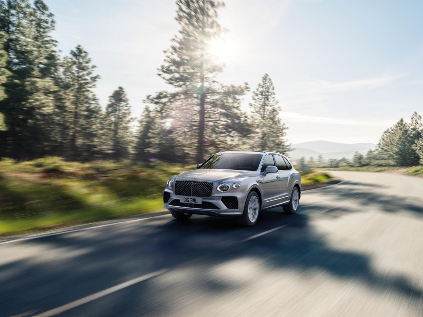 Front three - quarter view of Moonbeam coloured Bentley Bentayga driving along a road featuring matrix upper and lower grille.