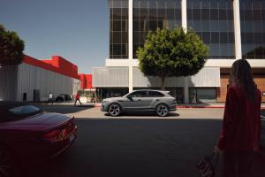 Front side angled view of Bentley Bentayga Speed in Orange Flame colour featuring Matt black matrix grille and 22 inch Alloy wheels driving along a highway.