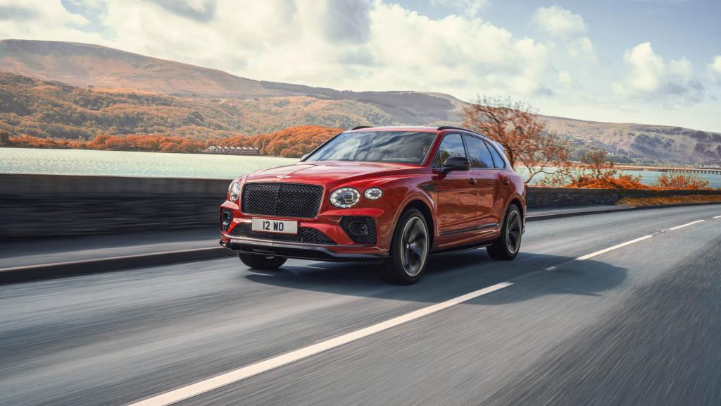 Bentley Bentayga S in Dragon Red featuring black matrix upper and lower grille driving along a road. 