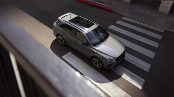 Top view Bentley Bentayga S in Cambrian Grey paint with sunroof in view driving through a zebra crossing.