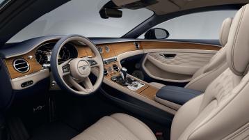 Interior view of Bentley Continental GT Azure from driver side, featuring Open Pore Koa Veneer and Portland Hide with steering wheel in view.