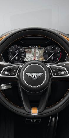 Close up on Beluga Hide for Bentley Continental GT Speed Heated, Single Tone, 3 Spoke, Indented Hide Trimmed Steering Wheel with dashboard gauges in view.