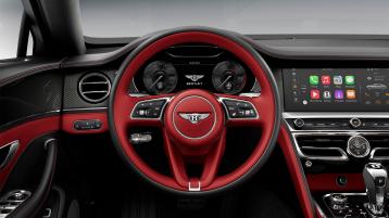 Driver side view of Bentley Flying Spur S V8 overlooking a Duo-Tone, 3 Spoke, Hide Trimmed Steering Wheel in Hot Spur and Beluga hide and High Gloss Carbon Fibre veneer.