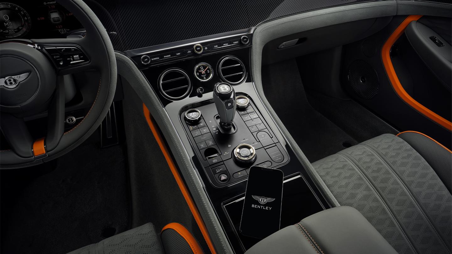 Iphone with the My Bentley App on the centre console of the new hybrid Bentley Continental GT Speed with Gravity Grey main hide and Mandarin secondary hide