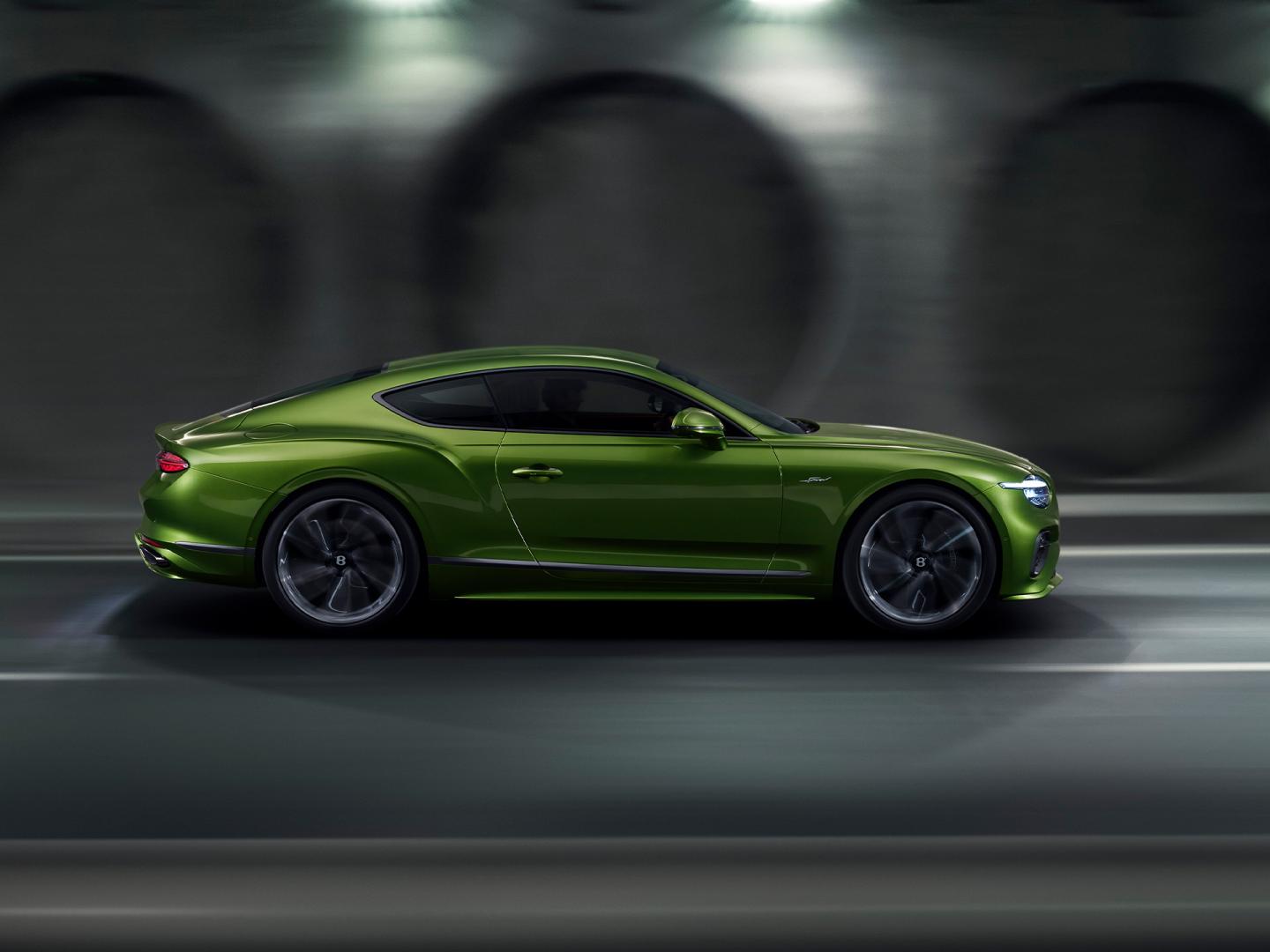 The new Hybrid Bentley Continental GT Speed in Tourmaline Green driving in an urban environment