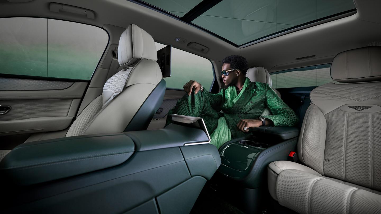 Wisdom Kaye sitting in the rear cabin of the Bentayga Atelier Edition with Portland main hide and Cumbrian Green secondary hide