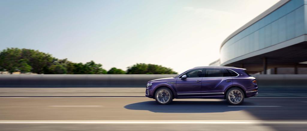 Side angled view of Bentley Bentayga EWB Mulliner in Tanzanite Purple driving along highway.