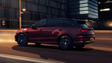Bentley Bentayga EWB Mulliner with Black Crystal over Cricket Ball exterior paint featuring 22 inch Mulliner Wheel - Black painted, driving in urban area.
