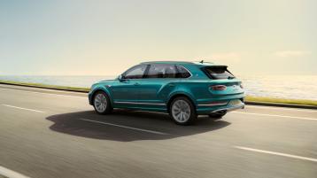 Rear side angled view of Bentley Bentayga EWB Azure in Topaz Blue with chrome accent, driving along sea side.