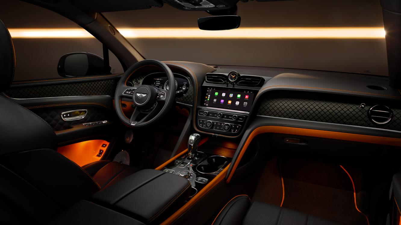 Interior front cabin view of Bentley Bentayga S, featuring Beluga leather and mandarin contrasting leather and Bentleys exclusive carbon weave on the dash fascia and in the door cards.