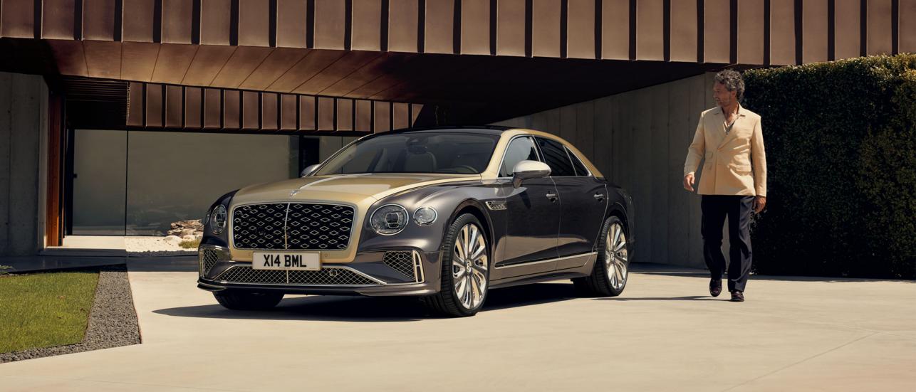 Side profile of the new hybrid Bentley Flying Spur in Tourmaline Green driving in an urban environment