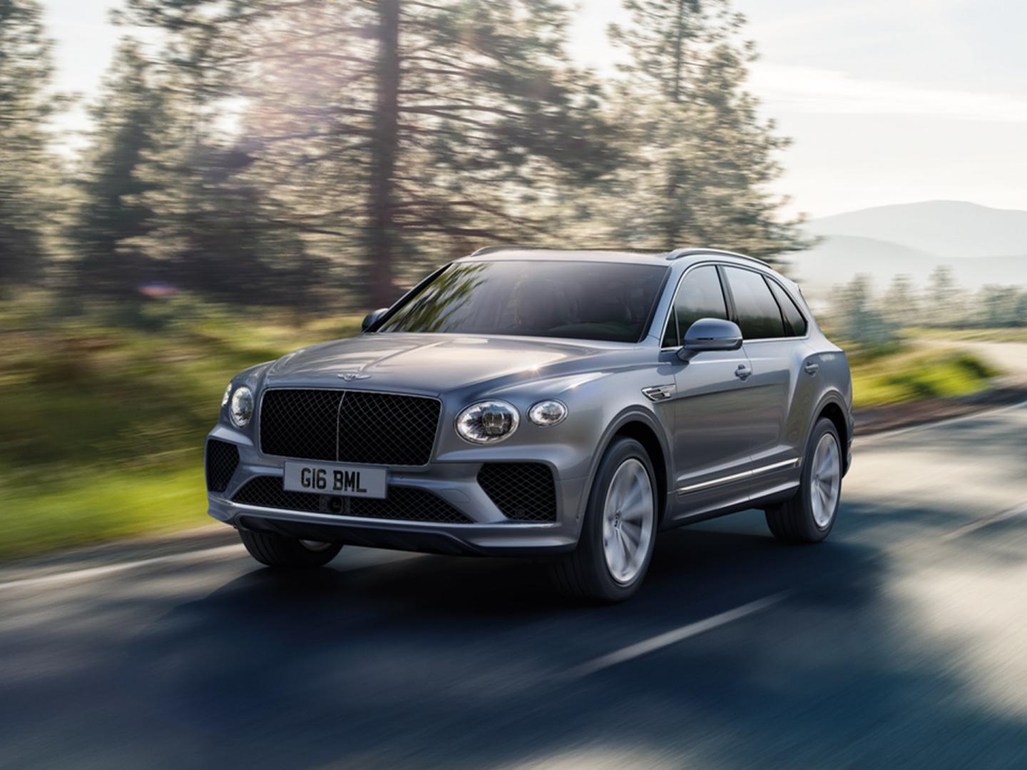 Front three - quarter view of Moonbeam coloured Bentley Bentayga driving along a road featuring matrix upper and lower grille.