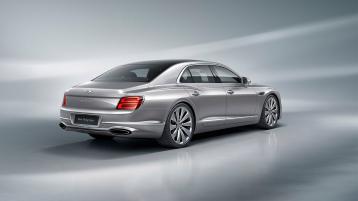 Rear three quarter of the new hybrid Flying Spur in the Moonbeam exterior colour and featuring directional 22' wheels