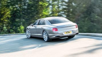 Rear of the new hybrid Bentley Flying Spur driving dynamically in a rural environment