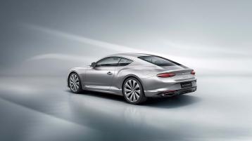Rear three quarter of the new hybrid Bentley Continental GT in a Moonbeam exterior featuring 22" directional wheels