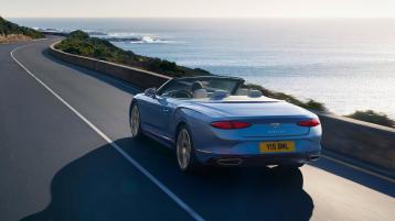 Bentley Continental GTC Azure in Topaz Blue colour with roof down featuring Black Gloss matrix grille with chrome surround and fluted vanes driving along sea side.