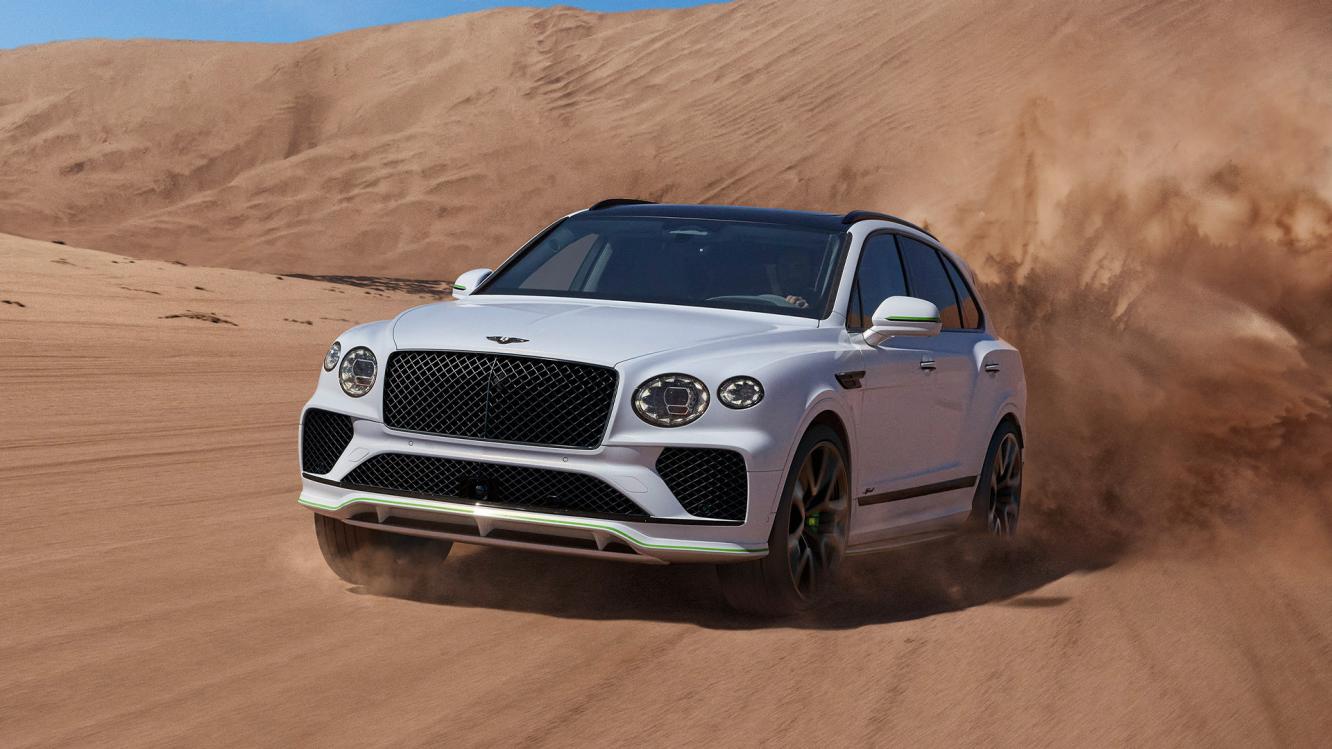 New Bentayga Speed in Snow Quartz by Mulliner exterior paint with the Bentayga Styling Specification and 23" Directional Wheels driving on sand dunes.