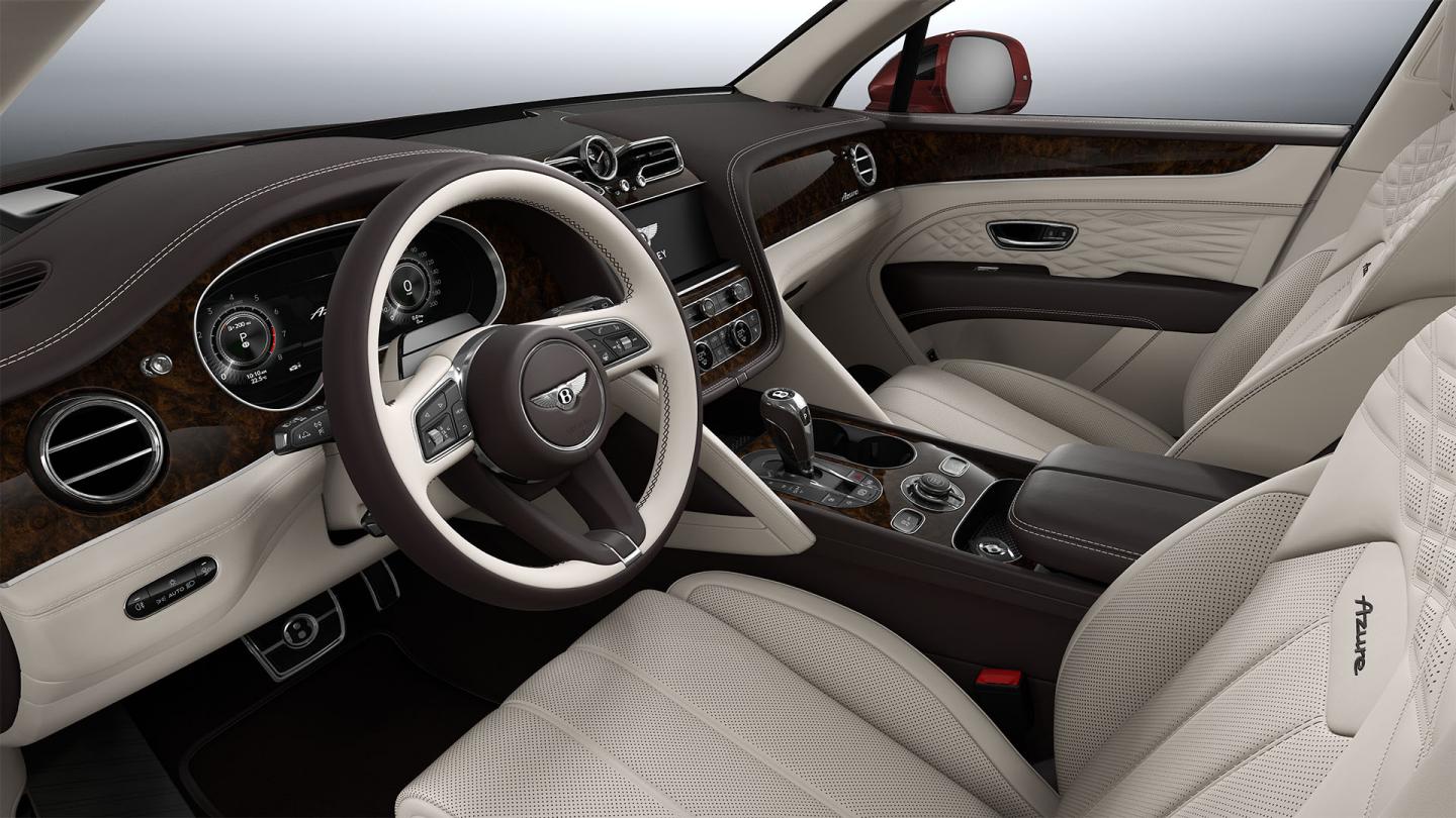 Interior passenger side view of Bentley Bentayga EWB Azure, featuring Open Pore Koa veneer with Azure Overlays below Chrome metal bulls-eye air vents.  