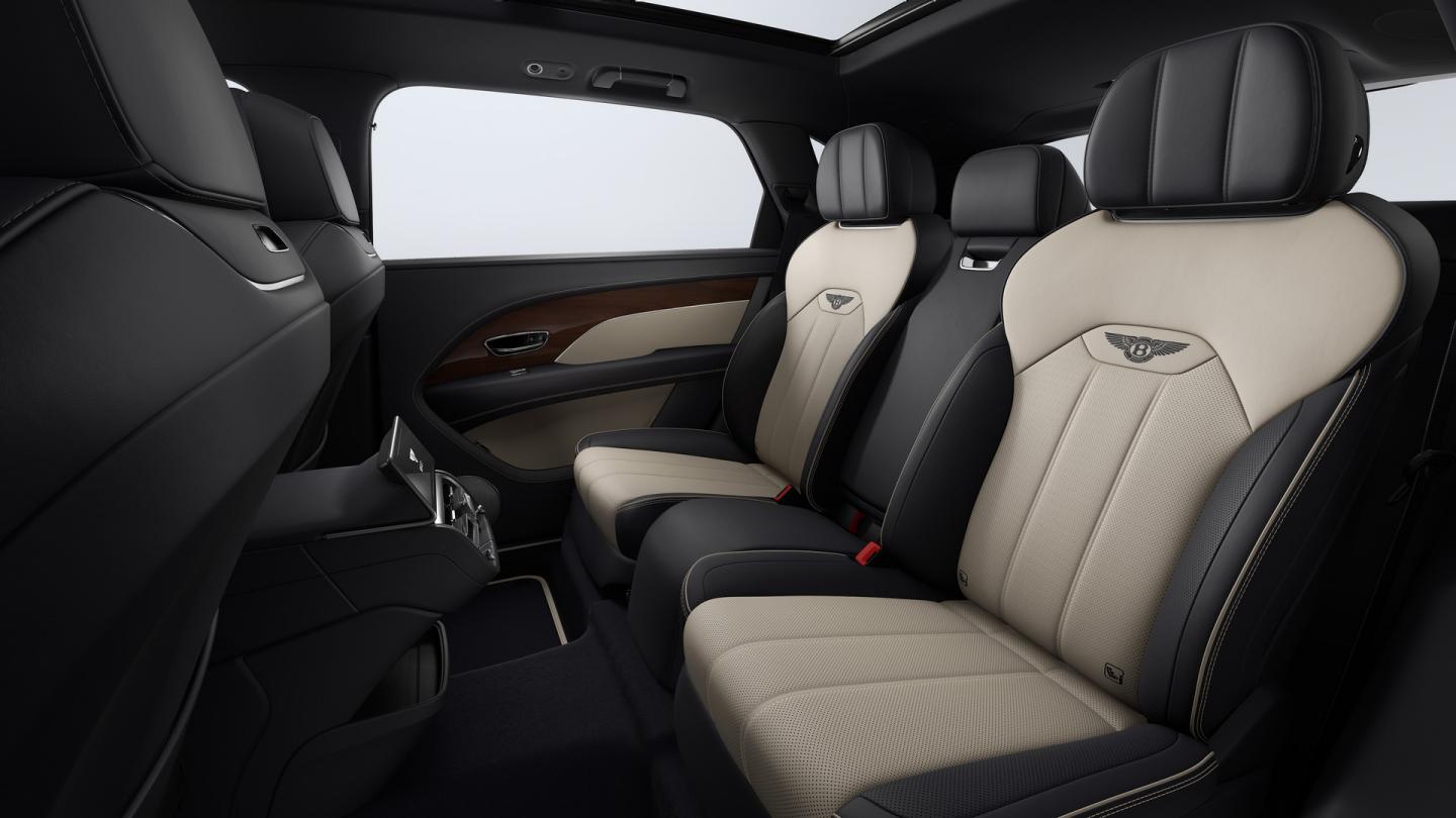 Bentey Bentayga EWB interior view for rear passenger seats featuring Bentley emblem in Linen contrast stitching over seats in Beluga hide 