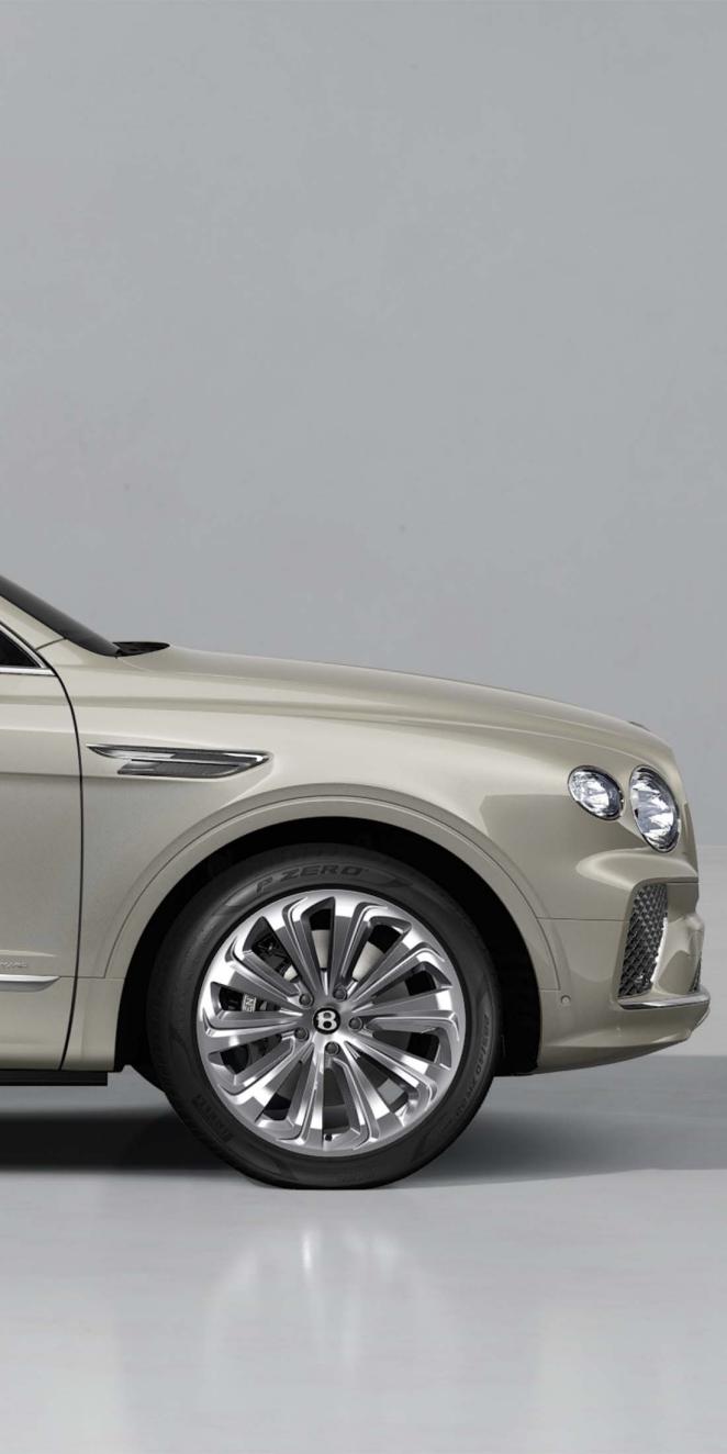 Front haunch of a Bentley Bentayga Azure in white sand exterior paint with 22" Ten Spoke Directional and Polished wheels
