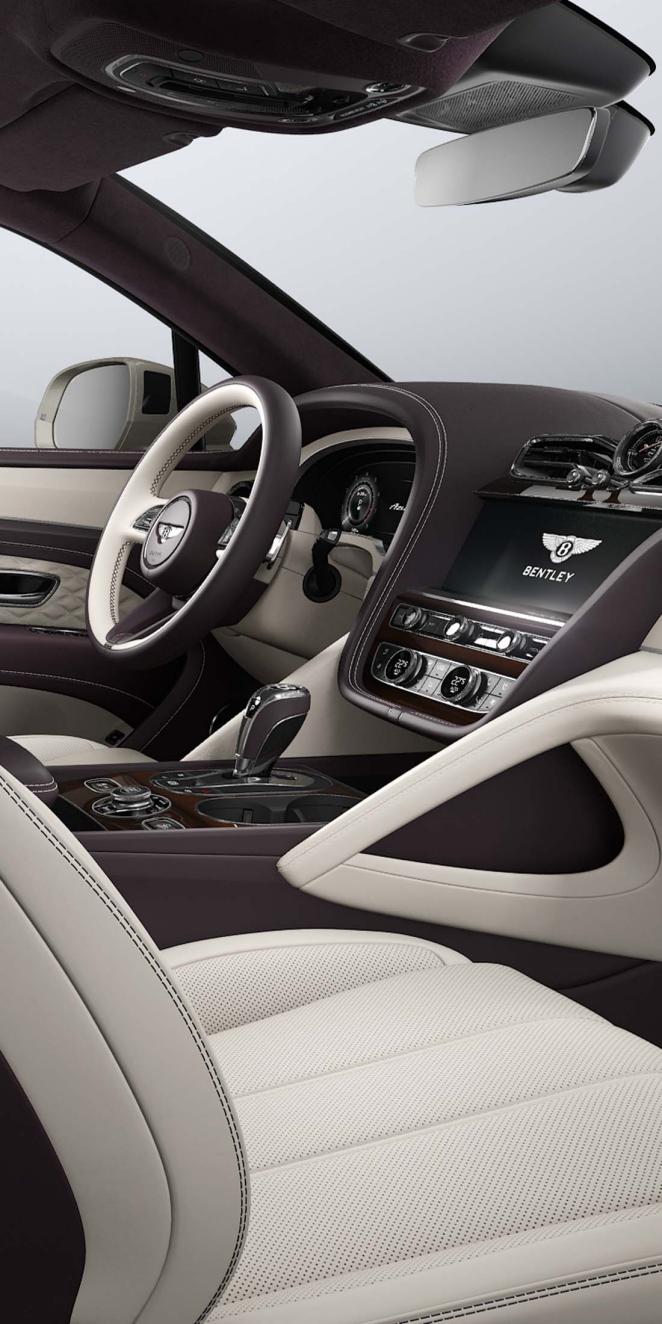 Passenger side view of Bentley Bentayga Azure overlooking a Heated, Duo Tone, 3 Spoke Hide Trimmed steering wheel and Open Pore Koa centre console.
