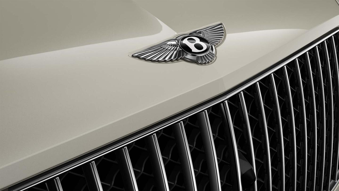Close up of the Bentley wings on the front bonnet of the Bentley Bentayga Azure with White Sand exterior paint