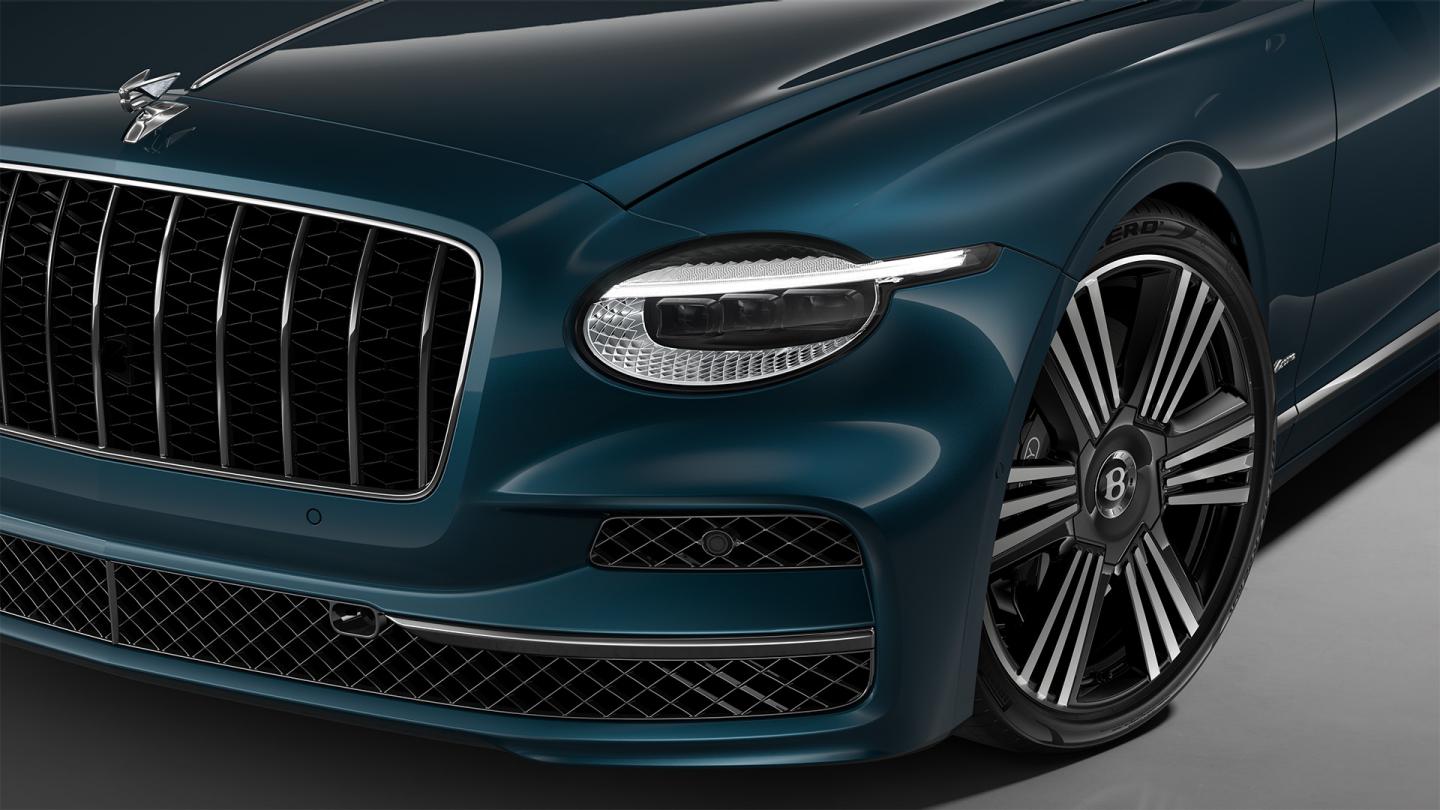 Front three-quarter close-up of the Bentley Flying Spur Azure in Dark Teal showing the headlights and 22" Azure Black & Machined wheel.