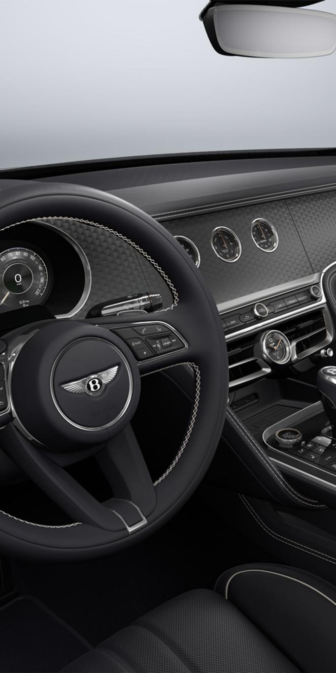 Driver's side view of the Bentley Flying Spur steering wheel with Dark Tint Engine Turned Aluminium veneer and rotating display visible.