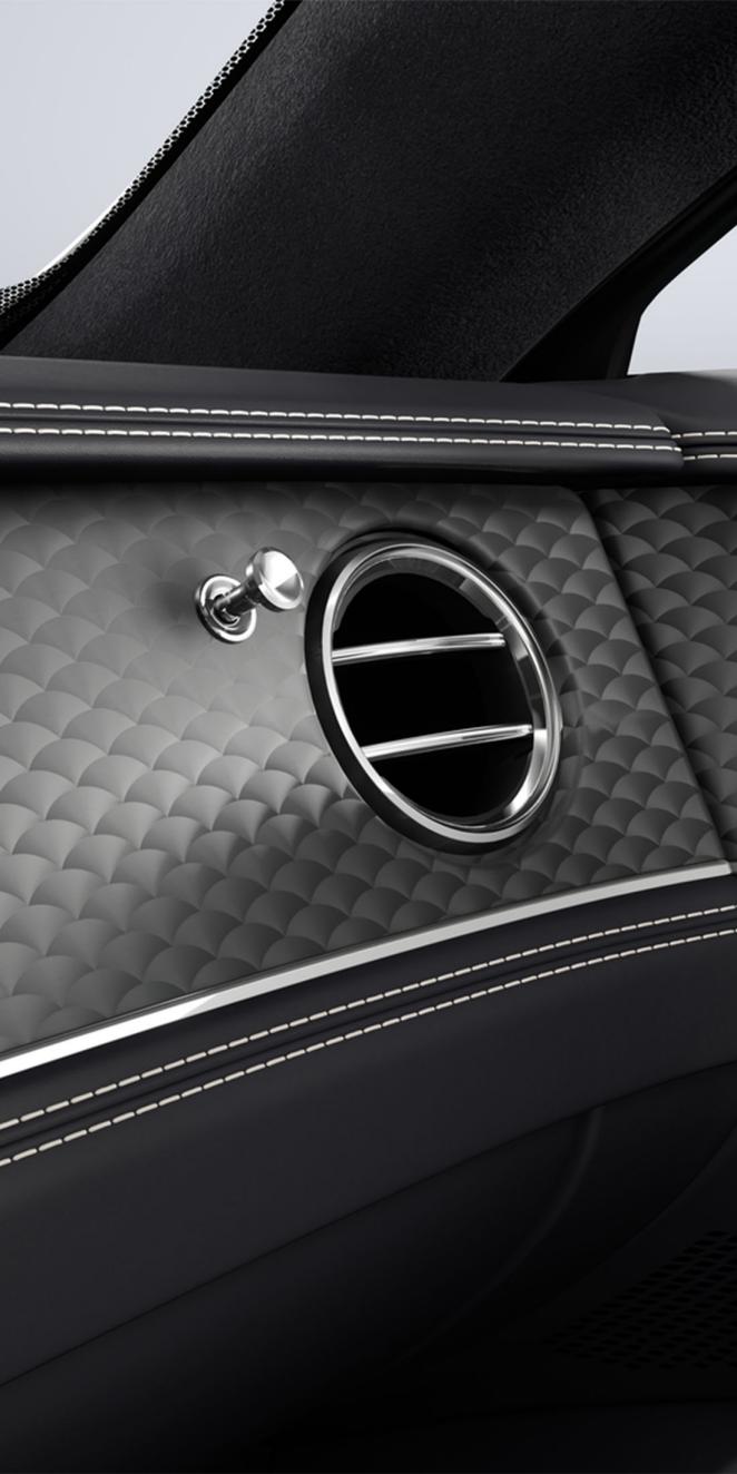 Close-up of the Dark Tint Engine Turned Aluminium veneer and air conditioning vent inside the Bentley Flying Spur.