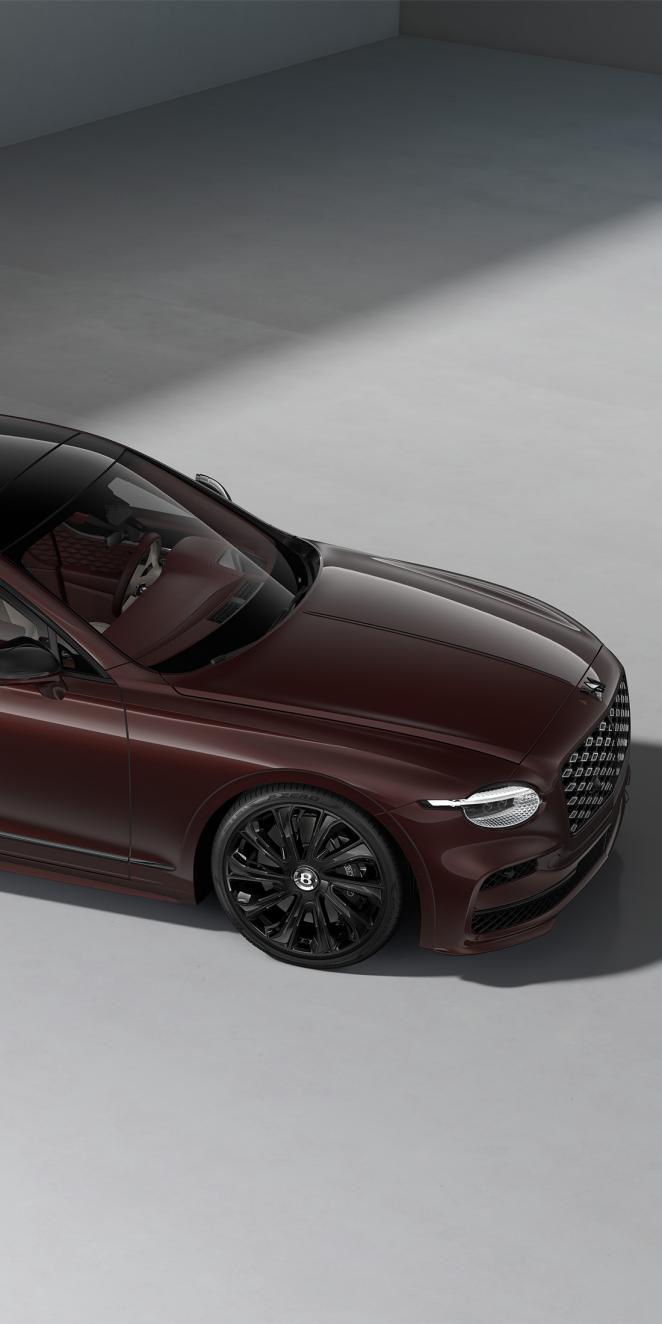 Front three-quarter close-up of the Bentley Flying Spur Mulliner in Cricket Ball showing the headlights and 22" Mulliner wheel painted in black.