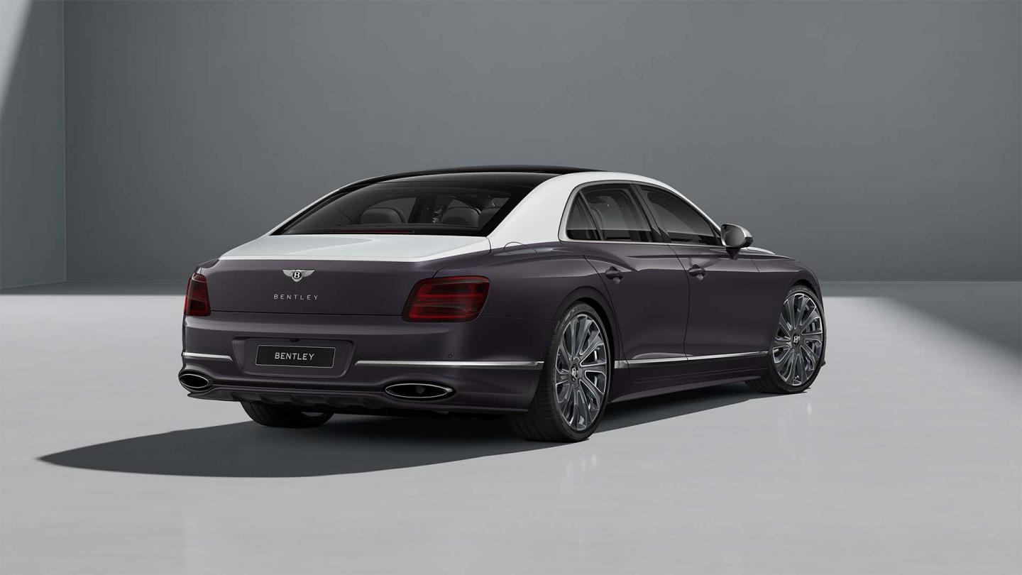 Rear three-quarter shot of the Bentley Flying Spur Mulliner in Ice / Grey Violet with Bright Chrome exterior detailing.