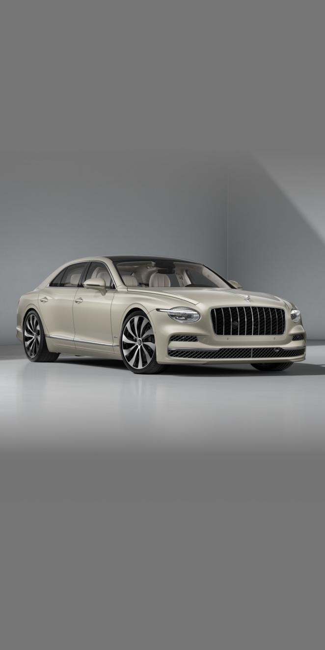 Front three-quarter of the Bentley Flying Spur Azure in White Sand showing the headlights and 22" Ten Spoke Wheel painted in black and bright machined.