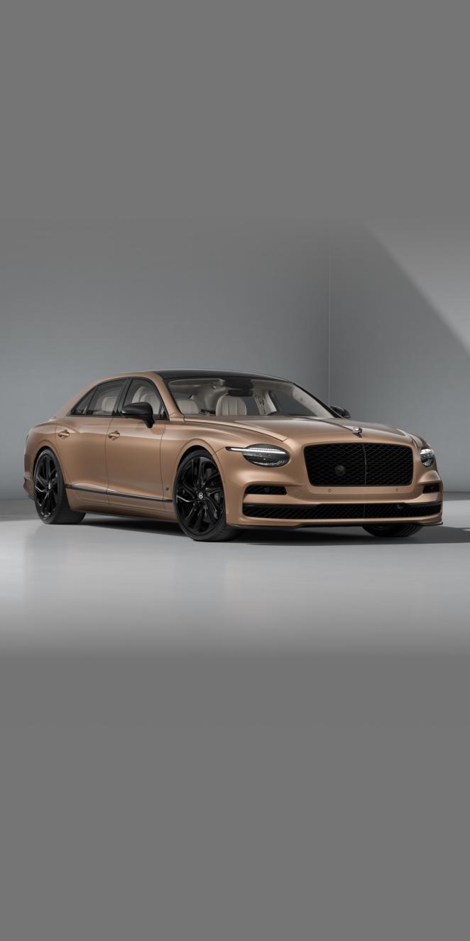 Front three-quarter of the Bentley Flying Spur S in Rose Gold showing the headlights, Carbon Styling Spec and 22" Ten Swept Spoke wheel painted in black.