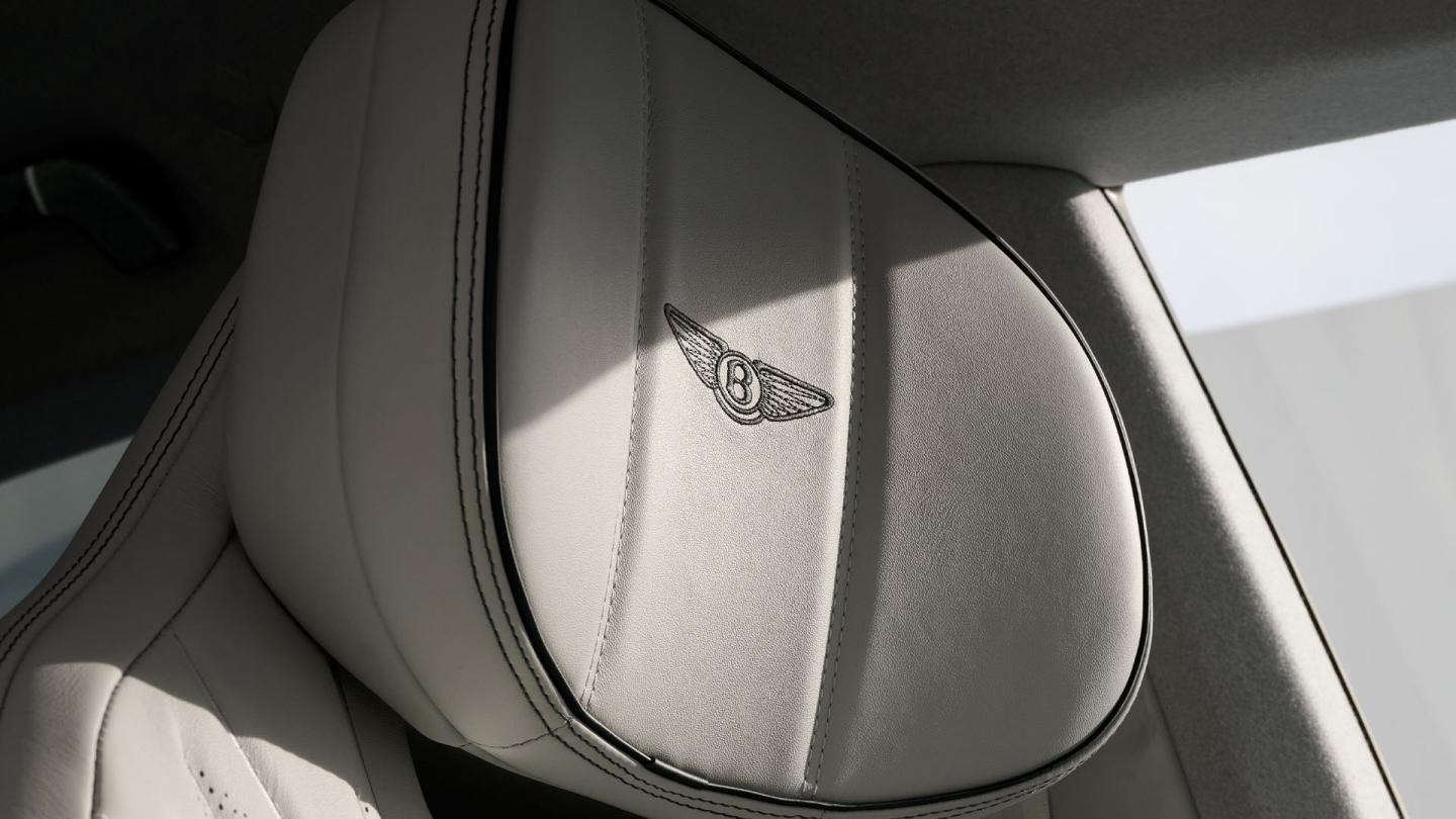 Close-up of the front seat headrest with embroidered Bentley Wings in the Bentley Torcal.