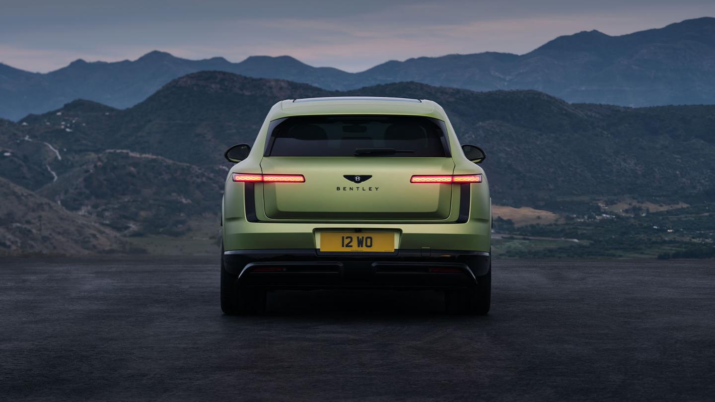 Rear view of the Bentley Torcal S in Electrum Satin driving on the road.