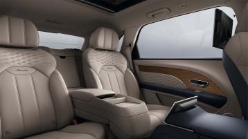 Bentey Bentayga EWB Azure interior view for rear passenger seats featuring Azure emblem in Imperial Blue, with Portland hide and Open Pore Koa veneer.