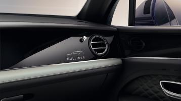 Interior passenger side view of Bentley Bentayga EWB Mulliner, featuring Grand Black veneer with Mulliner Overlays below Chrome air vents.