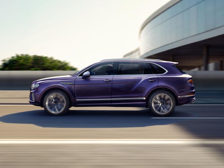 Bentley Bentayga EWB Mulliner side view in Tanzanite Purple with chrome accents driving along a highway.