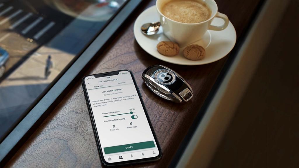 Smartphone featuring My Bentley App and Bentley Key fob in view with a cup of coffee