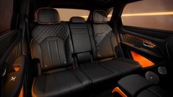 Interior rear cabin view of Bentley Bentayga S, featuring Beluga leather and mandarin contrasting leather and Bentleys exclusive carbon weave in the door cards.