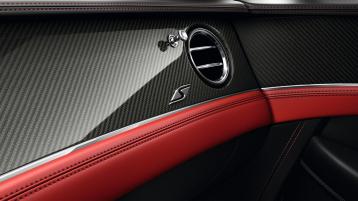 Close up interior view of Bentley Continental GTC S, featuring- High Gloss Carbon Fibre veneer and Metal bulls-eye vents with organ stops above S fascia badge.