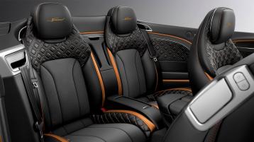 Rear passenger seats of Bentley Continental GTC Spur Speed in Mandarin by Mulliner Hide with seat piping and contrast stitching featuring Speed emblem.