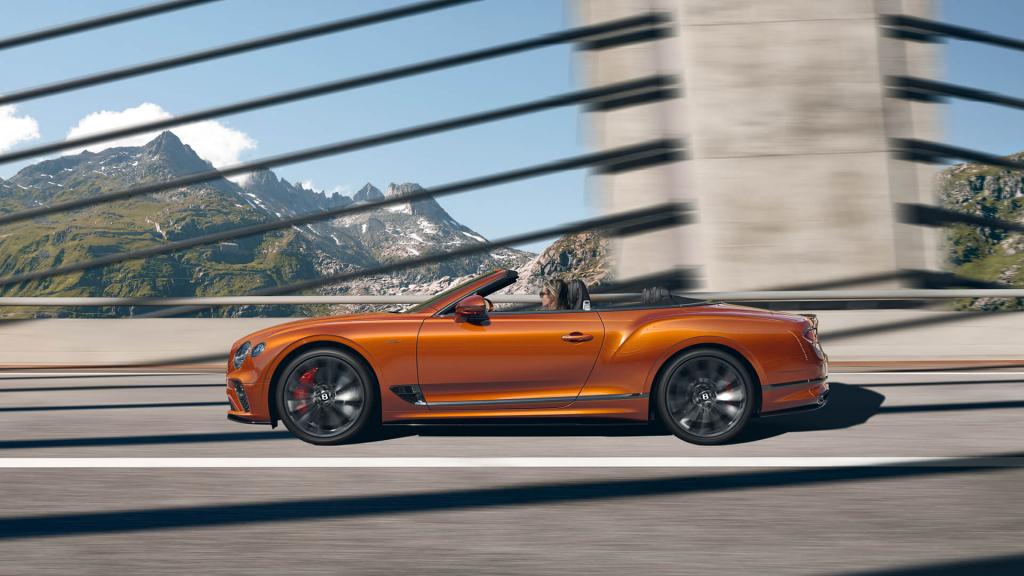  Side view of Bentley Continental GTC Speed W12 in Orange Flame colour, featuring 22 inch Speed Wheel - Dark Tint driving on a bridge.