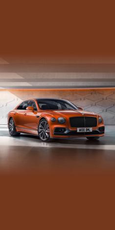 Front side angled view of Bentley Flying Spur Speed Edition 12 in Orange Flame, featuring 22 inch Speed Wheel- Dark Tint and matrix grille.
