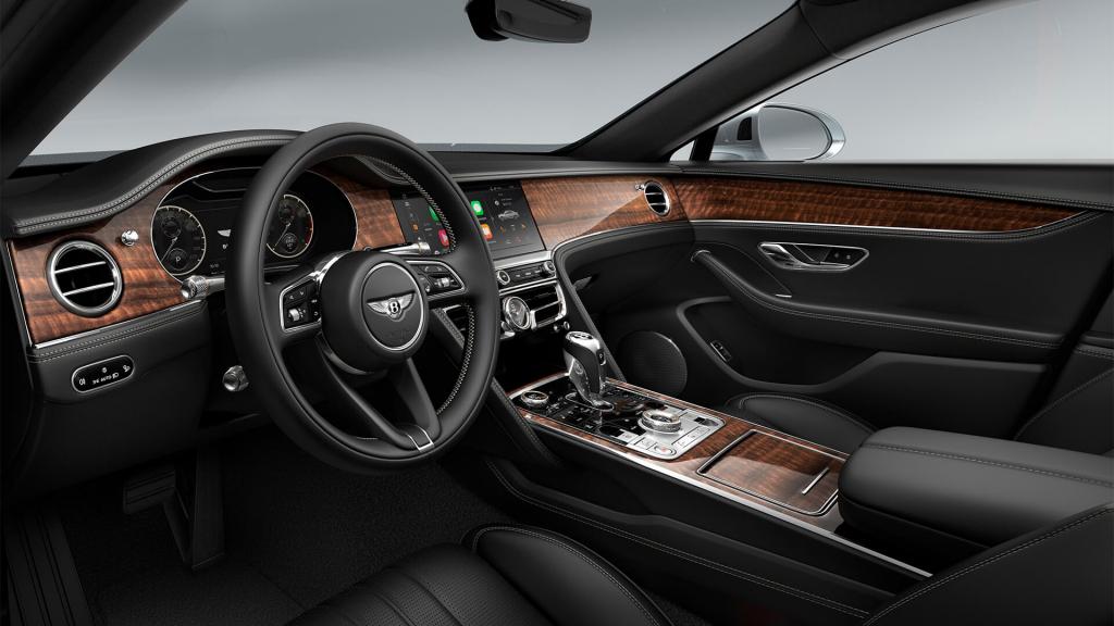 View over looking driver's seat of Bentley Flying Spur featuring Heated, Duo-Tone, 3 Spoke, Hide Trimmed Steering Wheel with Open Pore Koa Veneer.