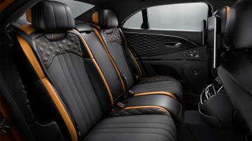 Rear passenger seats of Bentley Flying Spur Speed in Mandarin by Mulliner Hide with seat piping and contrast stitching featuring Speed emblem.
