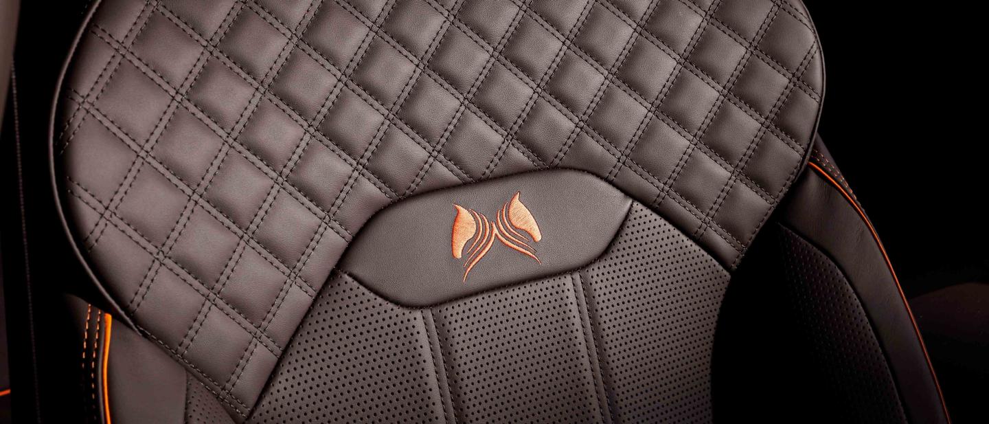 Bentley Bentayga EWB's front seat in focus, featuring detailed Diamond quilt detailed stitching and Orange flame piping witch custom emblem.