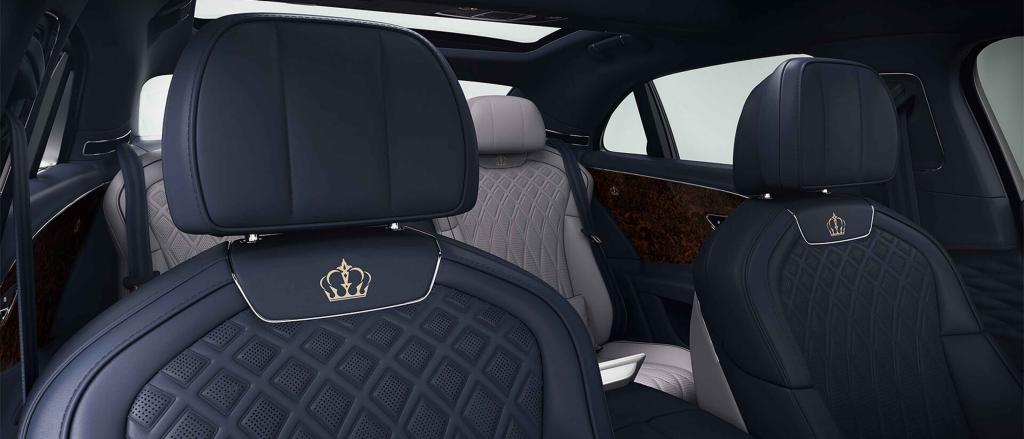 Front seats of Bentley Flying Spur Speed featuring lofted diamond-quilted seats in Damson hide with custom emblem. 