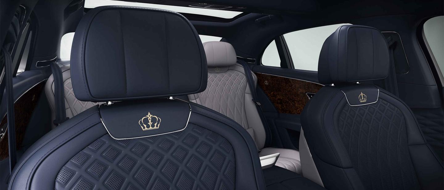 Front seats of Bentley Flying Spur featuring lofted diamond-quilted seats in Damson hide with custom emblem. 
