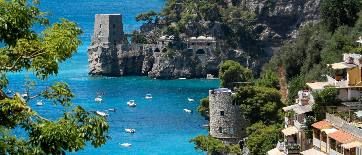 Close up of a coastline of Salerno, Italy, bordering the Mediterranean Sea, with boats in the water.